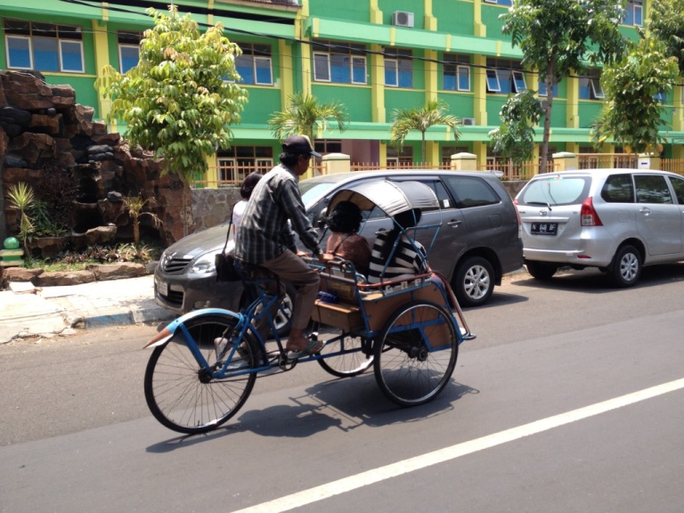 Un becak, une grosse voiture à Malang en Indonésie
