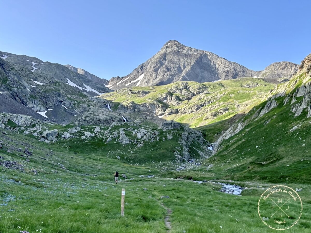 Prairie d'herbe verte, avec torrent, sous un sommet dans les Pyrénées